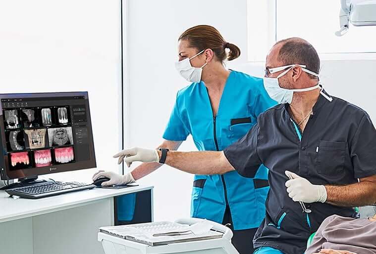 dentist and assistant looking at images of a patient's teeth