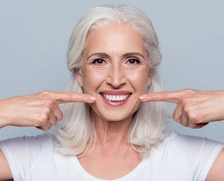 woman pointing at her bright, white smile