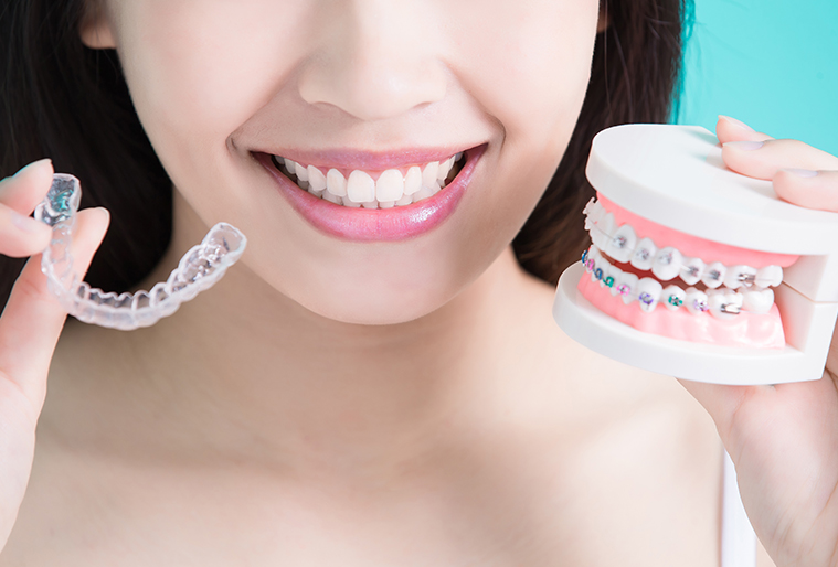 woman with straight smile holding invisalign and braces